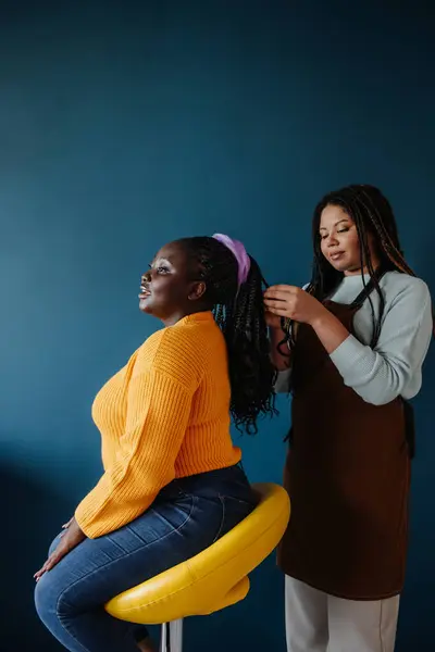 Cabeleireiro Africano Confiante Trançando Cabelo Para Cliente Feminino Fundo Azul — Fotografia de Stock