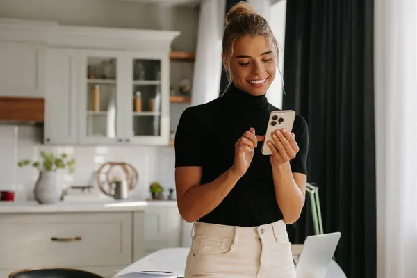 Giovane Donna Sicura Utilizzando Smart Phone Sorridente Mentre Piedi Casa — Foto Stock