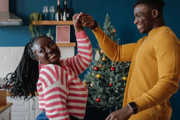 Mutlu genç Afrikalı çift evde birlikte yeni yılı kutlarken dans edip gülümsüyor.