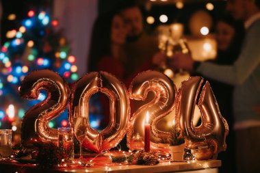 Mutlu gençler yeni yılı ön planda 2024 numaralı altın balonlarla kutluyorlar.