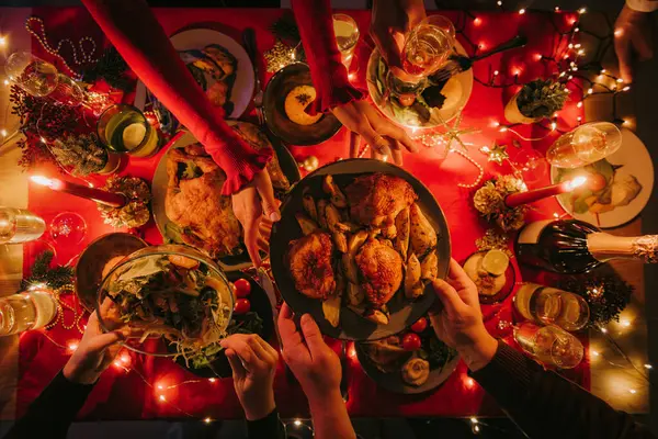装飾されたテーブルで休日のディナーをしながら さまざまなクリスマス料理を楽しんでいる人々のトップビュー — ストック写真