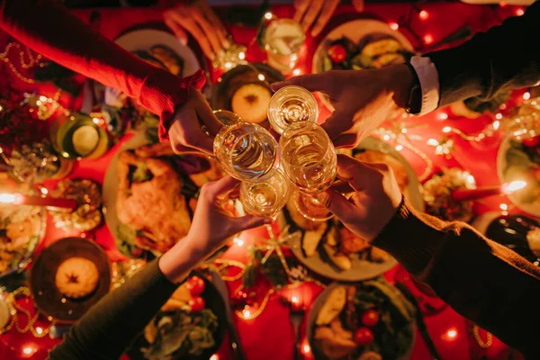 Top view of people toasting with champagne while enjoying New Year Eve at the decorated holiday table