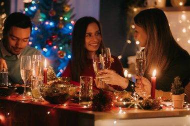 Gençler Noel masasında birlikte otururken şampanya içip eğleniyorlar.