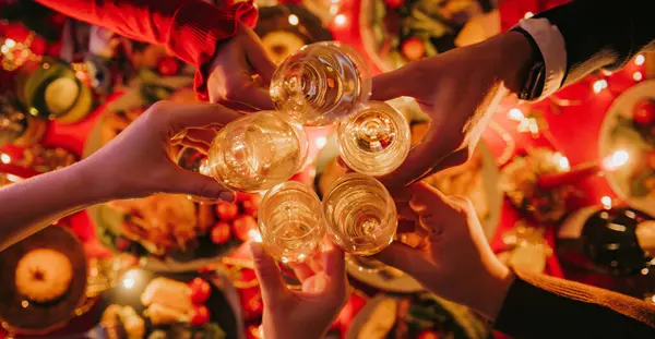 Top view of people toasting with champagne while enjoying Christmas Eve at the decorated holiday table