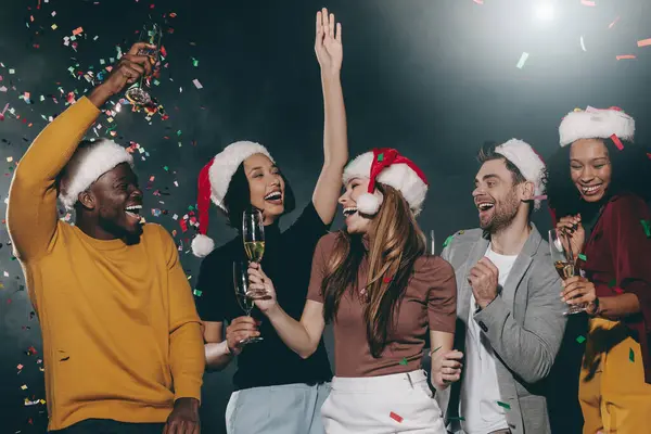Glada Unga Människor Julen Hattar Dansa Och Kasta Konfetti Samtidigt — Stockfoto