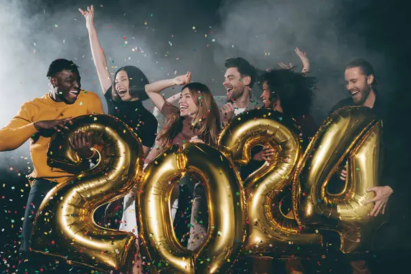 ナイトクラブでセッティを投げながら 2024年新年を祝う楽しい若者のグループ — ストック写真