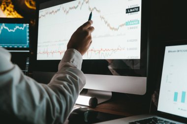 Gece ofisindeki borsa verilerini analiz ederken bilgisayar monitörünü gösteren erkek finans simsarının yakın çekimleri