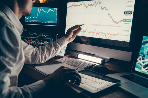 Close-up of male trader planning business strategy while pointing computer monitor in night office