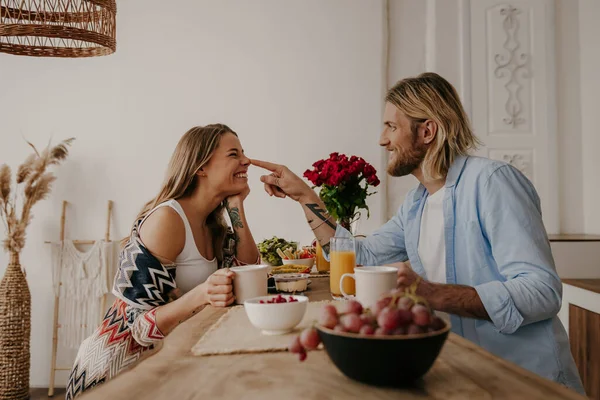 遊び心のある若い愛するカップルは ブーフスタイルの家で朝食を食べながら健康的な食べ物や飲み物を楽しんでいます — ストック写真
