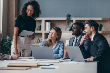 Ofis masasında takım toplantısı sırasında strateji tartışan gülen iş adamları grubu.