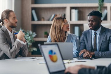 Ofis masasında grup toplantısı yaparken strateji tartışan kendine güvenen iş adamları.