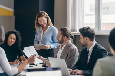 Ofiste takım toplantısı sırasında stratejiyi tartışan mutlu iş adamları grubu.