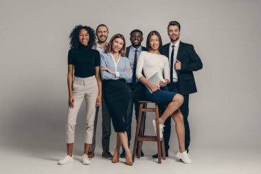 Formalite icabı giyinmiş genç bir iş adamı bej arka planda kameraya bakıyor.