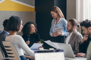 Ofiste takım toplantısı sırasında stratejiyi tartışan mutlu iş adamları grubu.