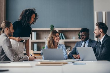 Ofis masasında takım toplantısı sırasında strateji tartışan mutlu iş adamları grubu.