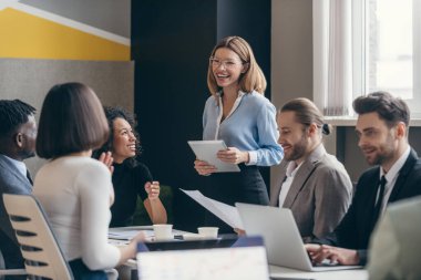 Ofiste takım toplantısı sırasında stratejiyi tartışan mutlu iş adamları grubu.