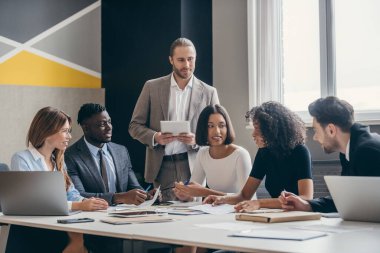 Modern ofiste birlikte çalışırken gülümseyen iş ekibi planlama stratejisi.