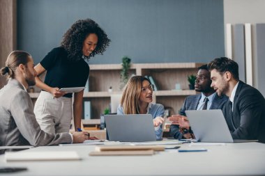 Ofis masasında takım toplantısı sırasında strateji tartışan kendinden emin bir grup iş adamı.