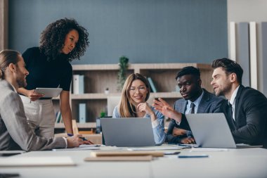 Ofiste takım toplantısı sırasında strateji planlayan konsantre bir grup iş adamı.