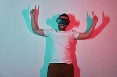 Sanal gerçeklikteki mutlu adam gözlükleriyle arka planda renkli gölgeler belirtiyor.