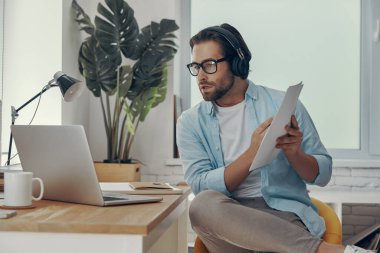 Ofisteki internet konferansı sırasında iş hakkında konuşan kulaklıklı kendine güvenen genç adam.