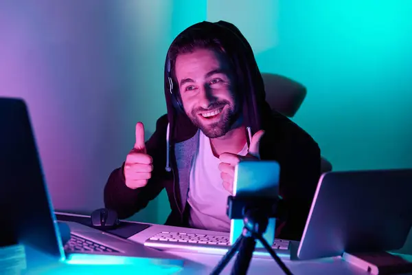 Happy young man looking at the computer monitor and gesturing against colorful background