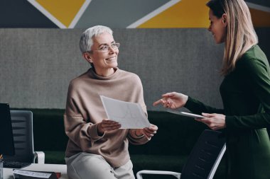 Ofiste çalışırken iş konuşan iki mutlu kadın.