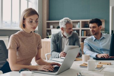 Ofisteki ortak masada otururken birlikte çalışan kendine güvenen bir grup iş adamı.