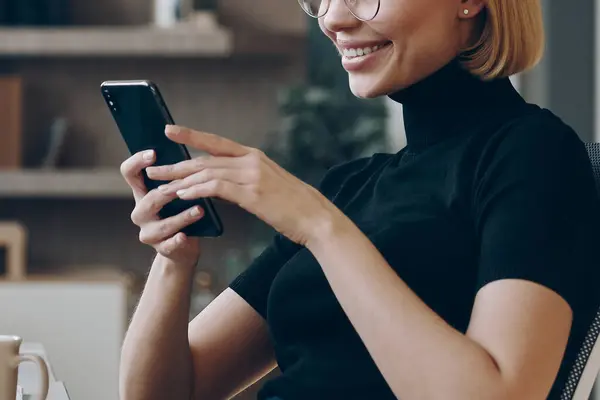Glad Ung Affärskvinna Som Använder Smart Telefon När Hon Sitter Stockfoto