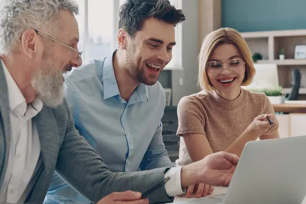 Drei Glückliche Geschäftsleute Schauen Büro Gemeinsam Auf Laptop Stockfoto