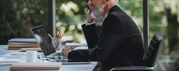 Selbstbewusster Reifer Geschäftsmann Der Sitzen Auf Seinem Arbeitsplatz Büro Telefoniert lizenzfreie Stockfotos