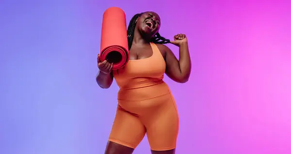 Stock image Happy African plus size woman in sportswear carrying exercise mat and smiling on vibrant background