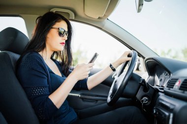 Kadın araba kullanırken mesajlarını kontrol ediyor..