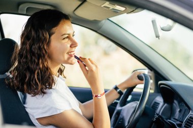 Bir kadının profil pozu dudaklarına kırmızı ruj sürüyor..