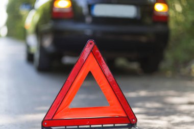 Yolun kenarında arızalı bir arabanın bulanık duruşu. Kırmızı tabelaya odaklan. 