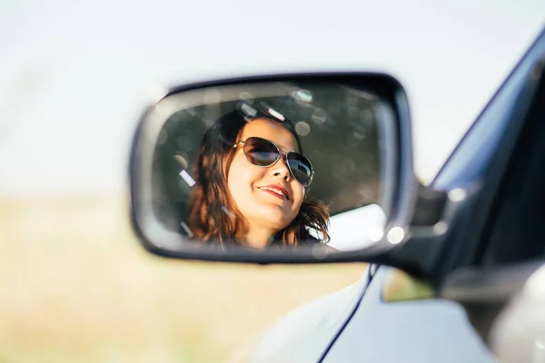Pose of the side car\'s mirror with a smiling woman reflecting on it