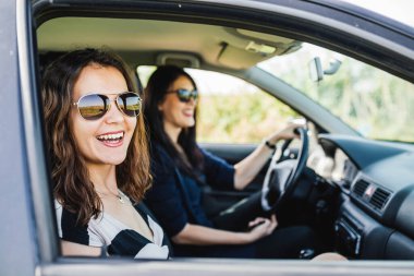 En büyükleri araba kullanırken iki genç bayanın profili gülüyor..