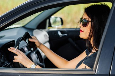 Şoför kadın araba kullanırken sigara içiyor..