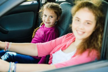 İki kız kardeş aile arabasında otururken kameraya gülümsüyor. En büyüğü bulanık..