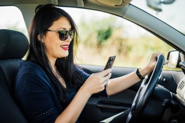 Lady driver has recently received a text message and now she is very happy.