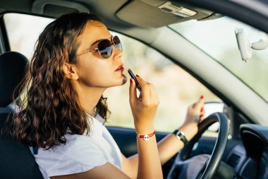 Woman distracted in car with cosmetics.