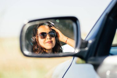 Reflection of caucasian woman in rearview mirror of a car.