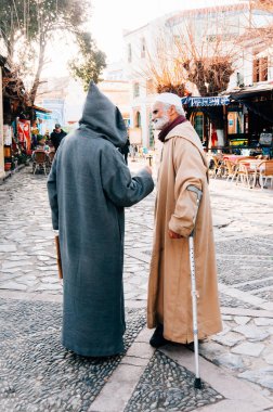 Şef, Fas... 11 Şubat 2015: Tipik Fas giysileri içinde kimliği belirsiz Müslüman bir adam, diğer bir adamla sokağın aşağısındaki eski mavi Şef Medine, Fas 'ta buluşuyor.