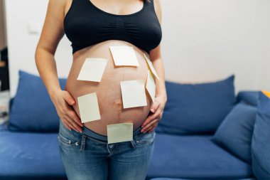 Karnında sarı yapışkan notlar olan ve çocuk bekleyen bir annenin gövdesi. .