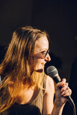 Stüdyoda güneş gözlüğü takan bir kadın sanatçının profil pozu.