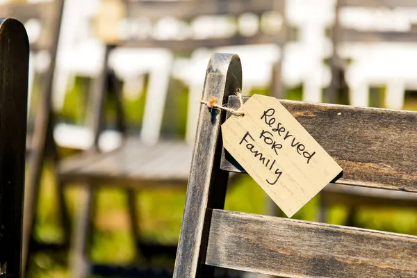 Tag style sign on a chair at a wedding ceremony says this seat is reserved for family.
