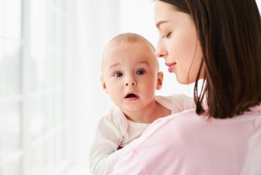 Genç anne kucak kucak kucak kucak kucak kucak kucak kucak küçük çocuk sevgi ve özenle. Bebek bakıcısının kucağında yeni doğmuş bir bebek var. Annelik ve evlat edinme kavramı.