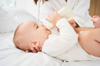 Genç, bekar bir anne dadının, küçük, çocuk, yeni doğmuş bir bebekle beslenen bebek bakıcısının kesilmiş portresi. Emzirme ve süt pompalama konsepti.