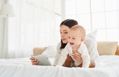 Beyaz önlüklü beyaz bir anne güneşli bir sabahta yeni doğmuş oğluyla yatakta vakit geçirir. Modern teknolojiyi kullanarak çocuk gelişimi. Çocuk bir video görüşmesinde konuşuyor..
