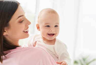 Gülen mutlu bir bebek, yeni doğmuş, beyaz elbiseli bir çocuk güzel beyaz bir anne, bekar bir anne, kollarında bir dadı. Pencerenin yanında duruyor..
